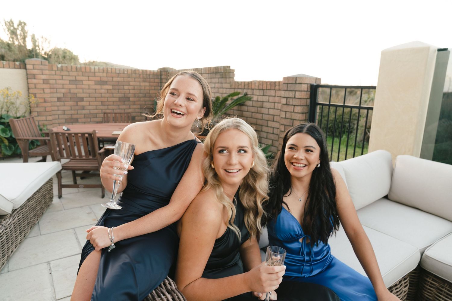 Friends enjoying drinks and conversation on outdoor terrace with brick walls.