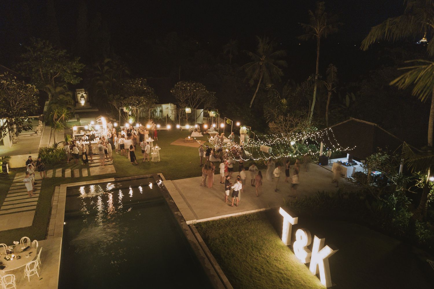 String lights illuminate an outdoor evening wedding reception area creating a warm ambiance.