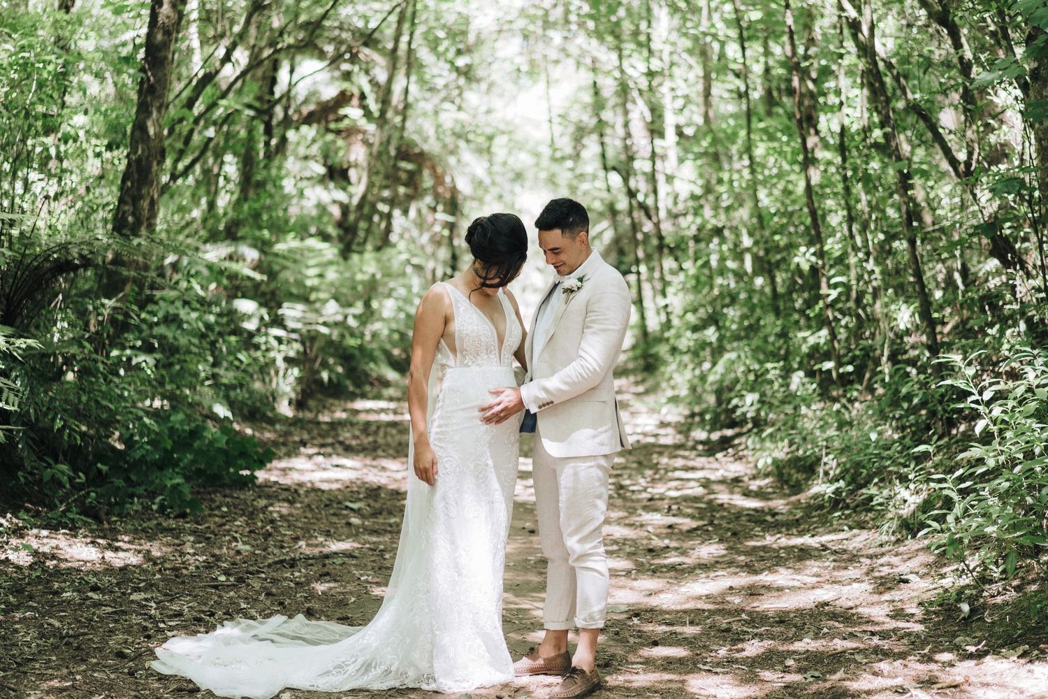 Wedding couple walking through a lush green garden path on their special day.