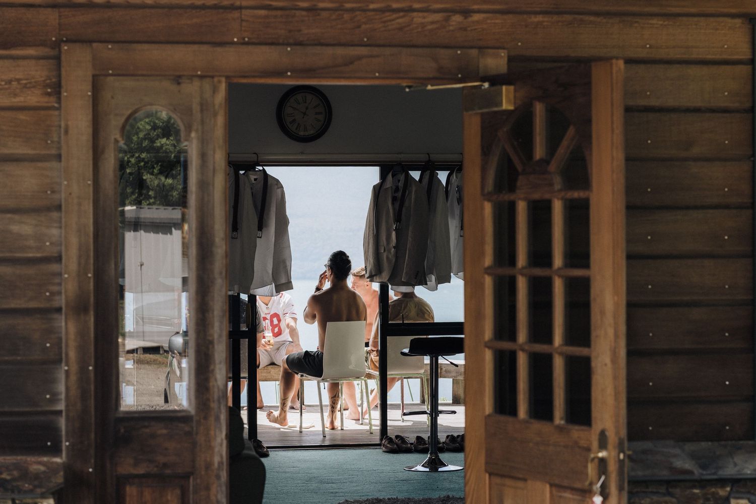 Two people stand in a doorway of a rustic wooden building, silhouetted against bright outdoor light.