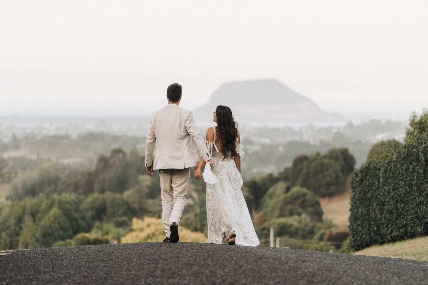 Couple stands together overlooking scenic mountain vista in formal attire.