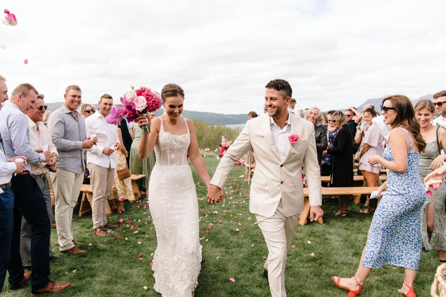 Wedding guests celebrate on a grassy lawn during a lively outdoor summer reception.