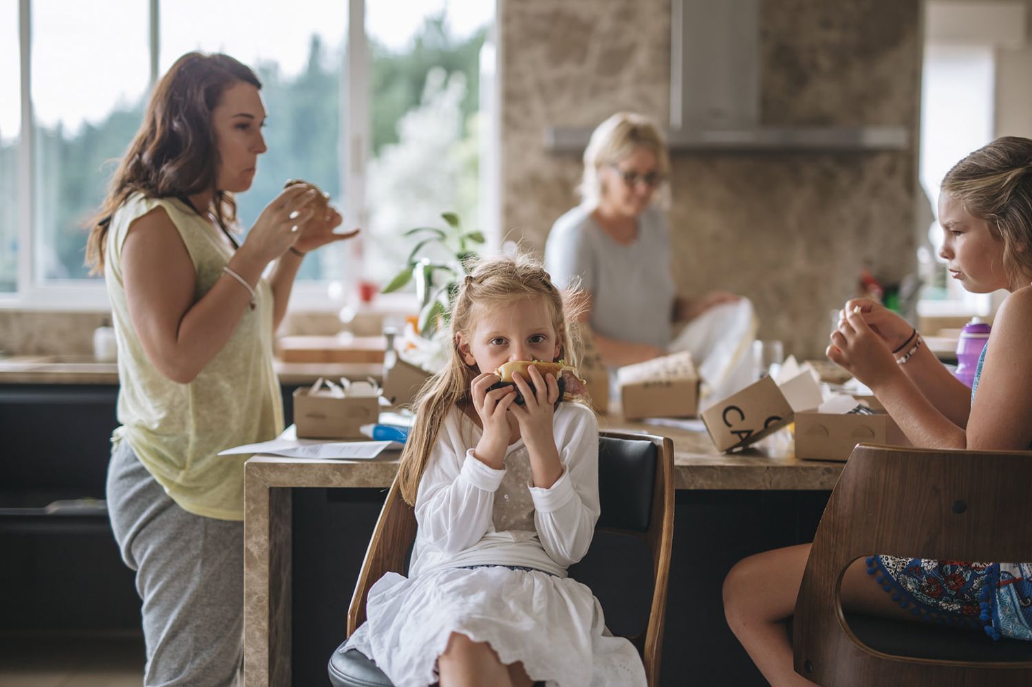 A group sits at a dining table sharing pastries and treats during a casual gathering at home.