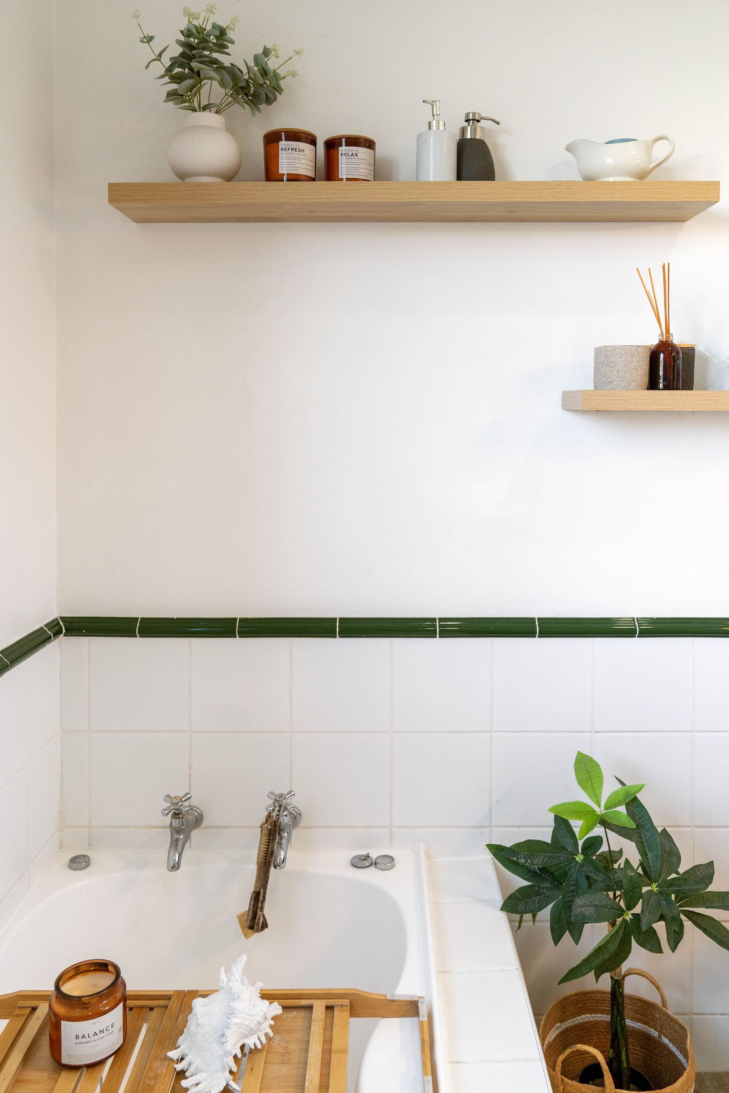 Modern bathroom with white tile, wooden floating shelves displaying plants and toiletries.