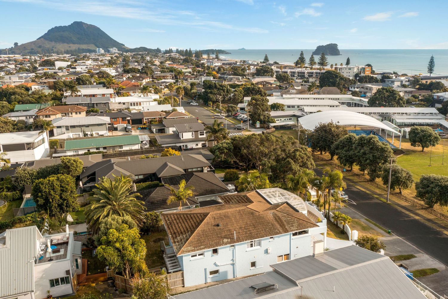 Aerial panoramic coastal landscape view of Mount Maunganui Tauranga New Zealand with beach and houses.