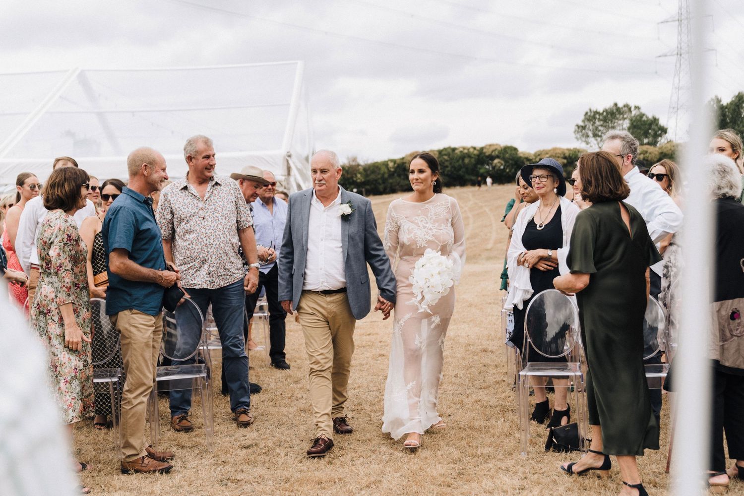 Wedding guests gather in casual attire at an outdoor hillside venue.