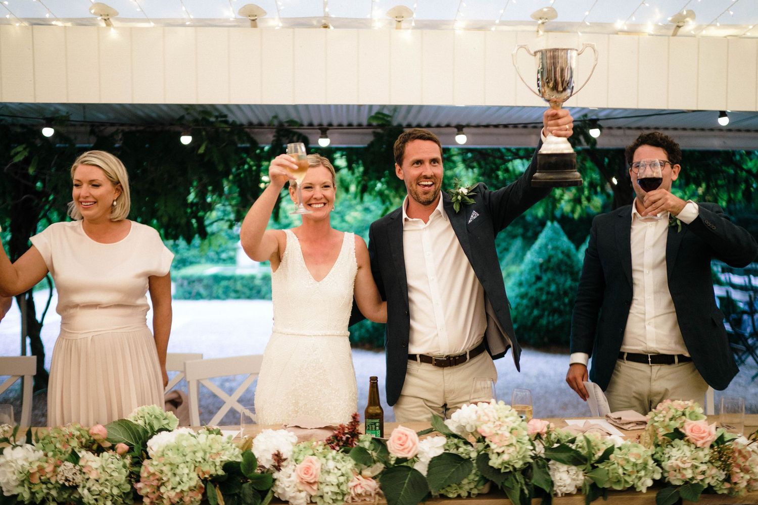 Wedding party raising their glasses in a celebratory toast at the head table.