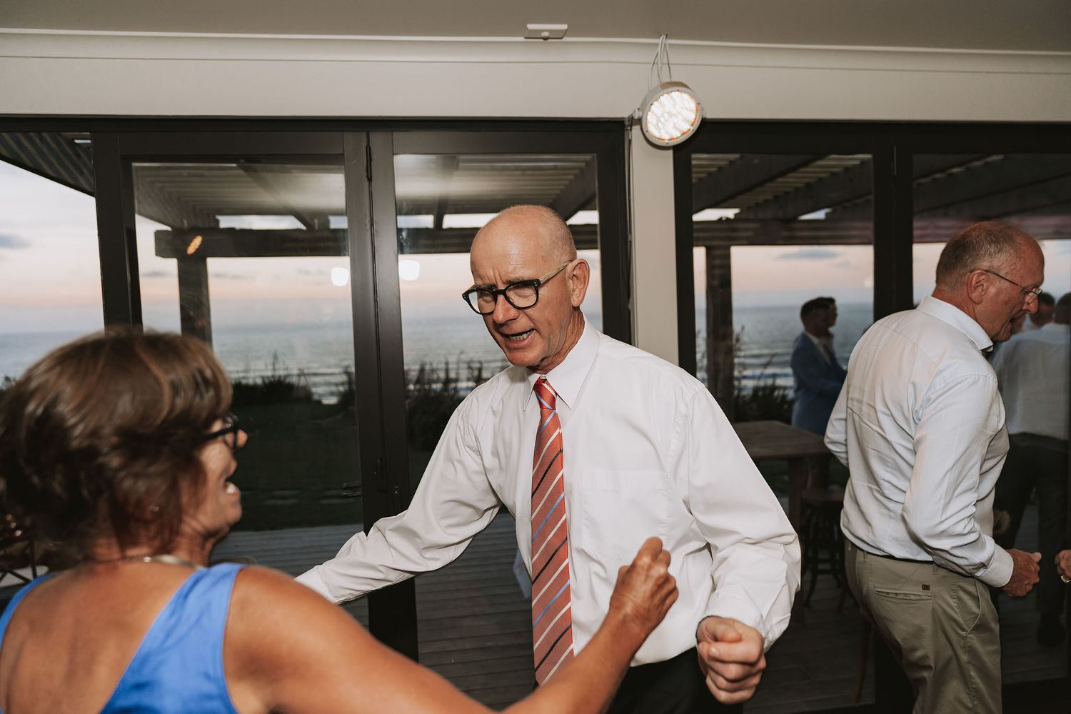 Two well-dressed people dancing and interacting in what appears to be a reception or party setting.