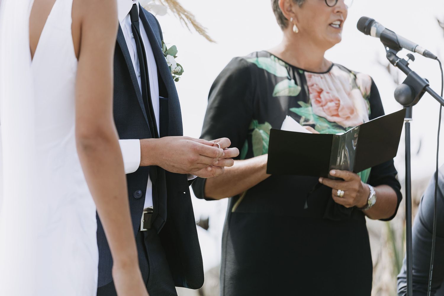 Two people in formal attire stand at microphones during what appears to be a wedding ceremony or speech event.