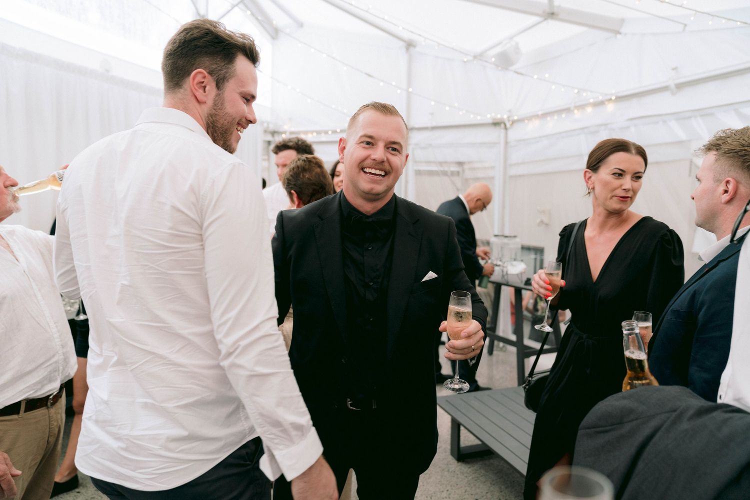 Guests enjoying casual conversation during a tented wedding reception.