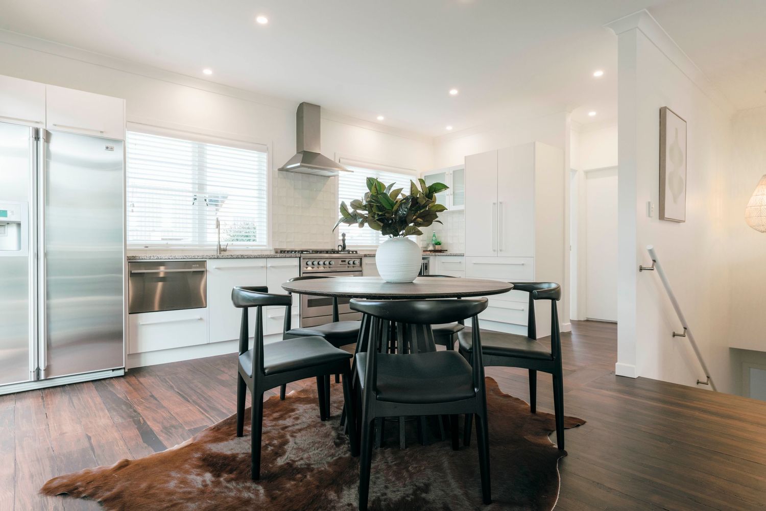 Contemporary open kitchen design with round dining table, black chairs and hardwood floors.