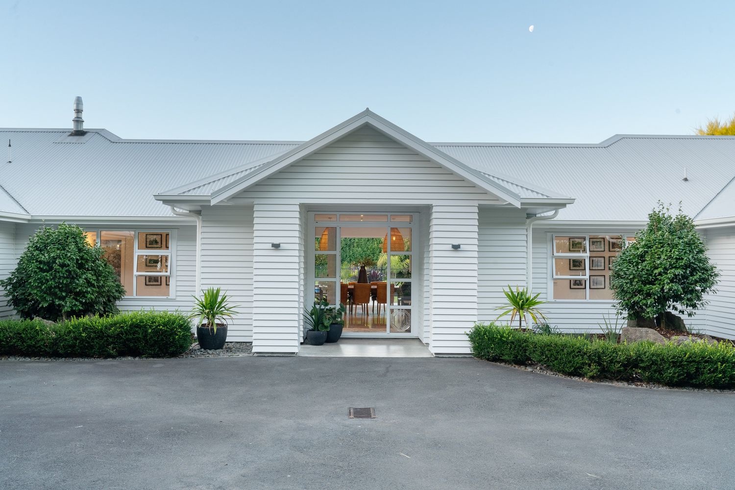White farmhouse-style home exterior with symmetrical entrance and manicured landscaping.