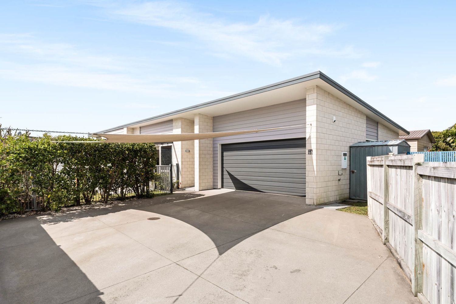 Modern white house exterior with gray garage door and concrete driveway.