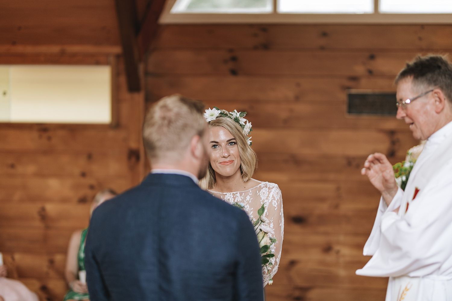 A couple exchanges vows during a rustic barn wedding ceremony with wooden walls and natural decor.