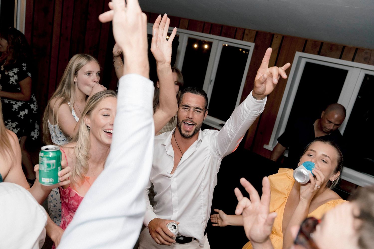 Wedding guests dancing and celebrating with enthusiasm during an indoor evening reception party.