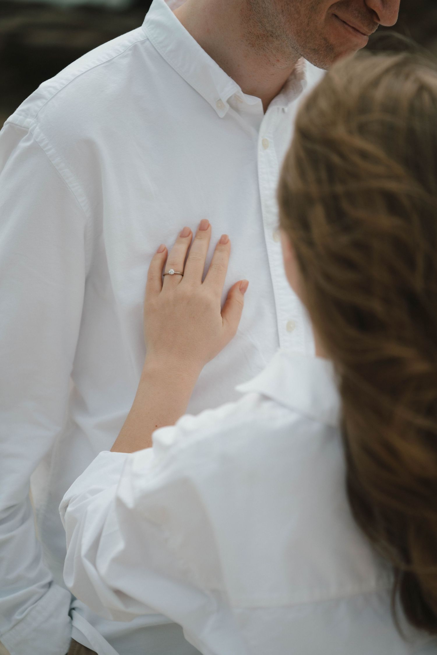 Close-up detail of a couple's intimate moment showing white clothing and gentle touch.