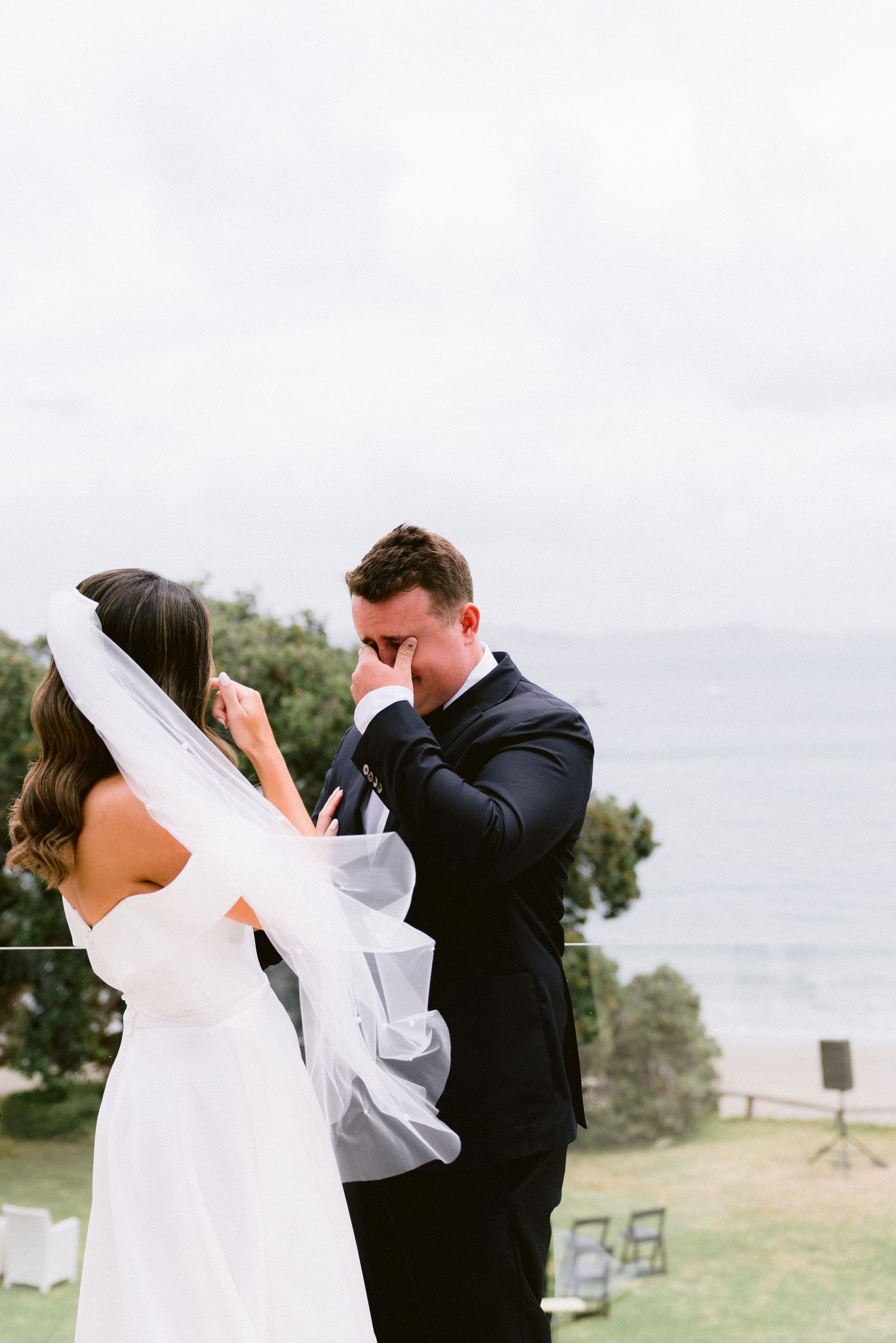 Bride and groom share a joyful first look moment in an outdoor garden setting.