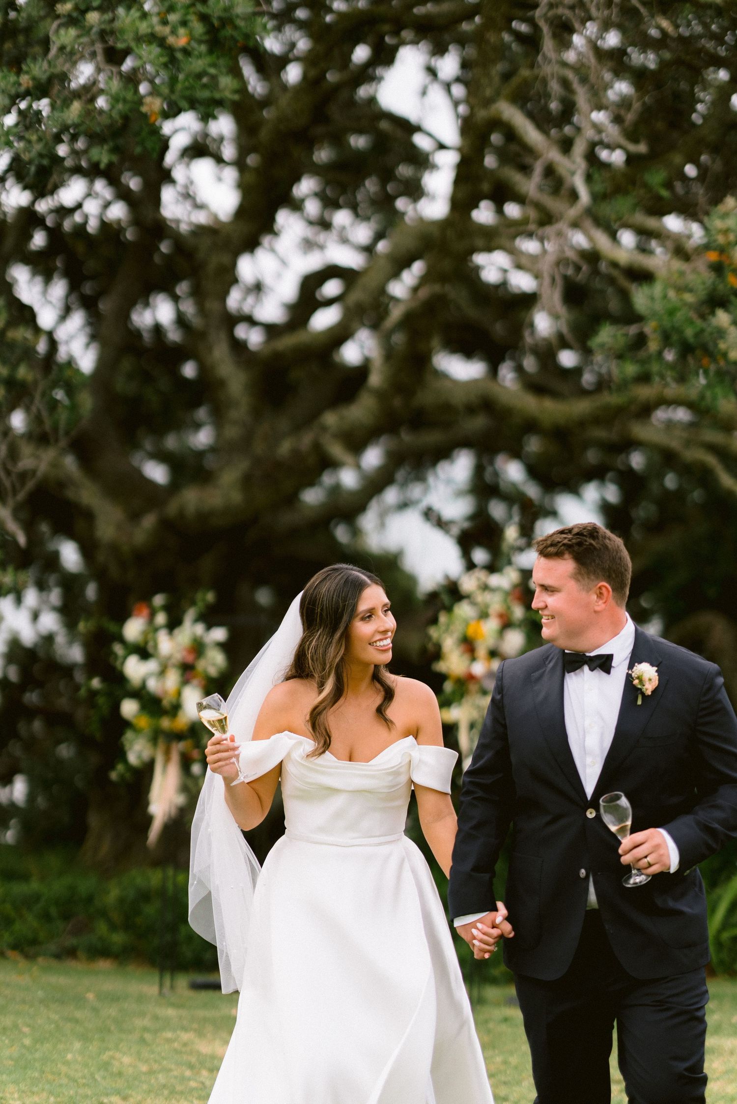 Elegant outdoor wedding celebration with champagne toast against a backdrop of greenery.