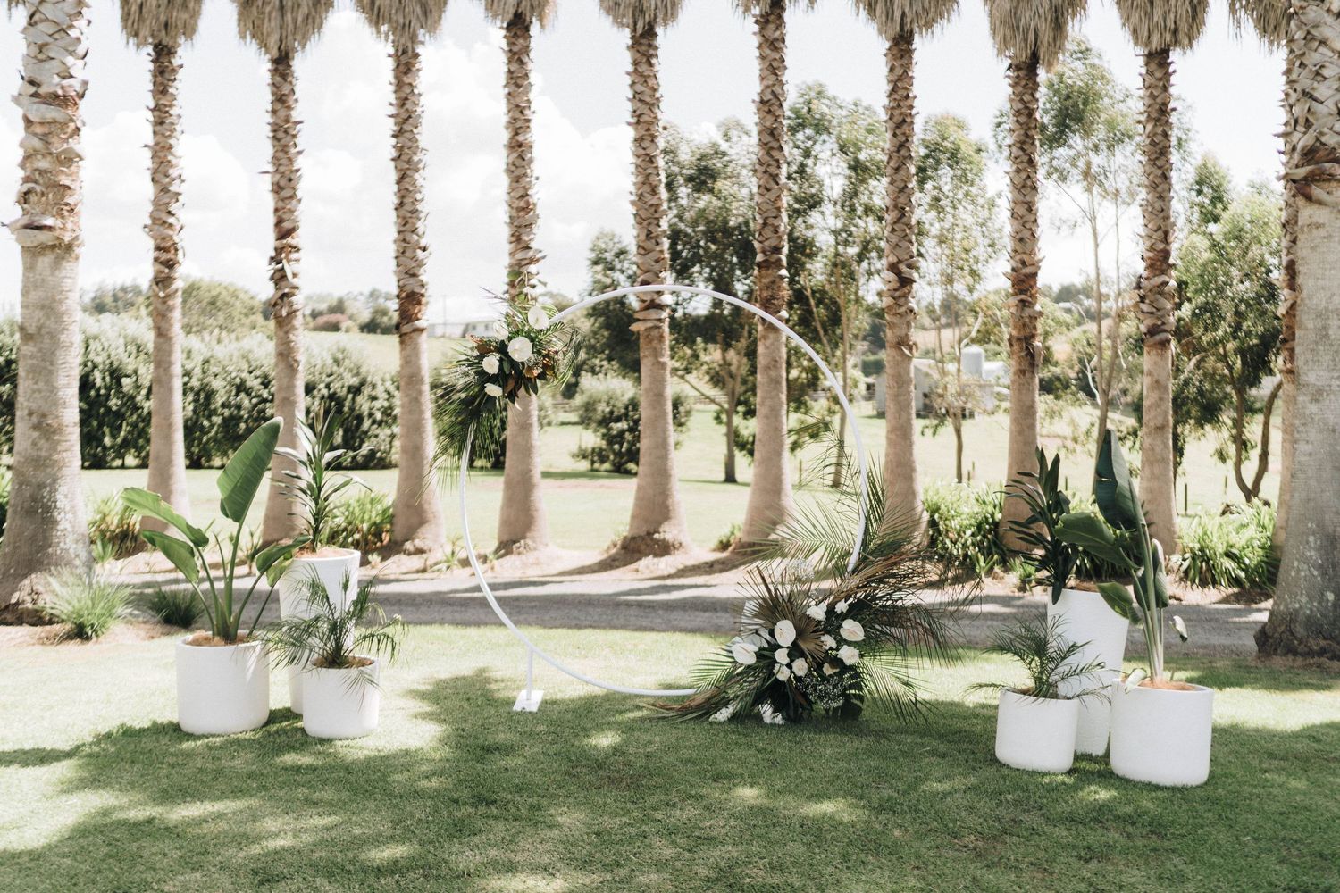 Palm tree-lined outdoor wedding venue with white tents and seating arrangements.