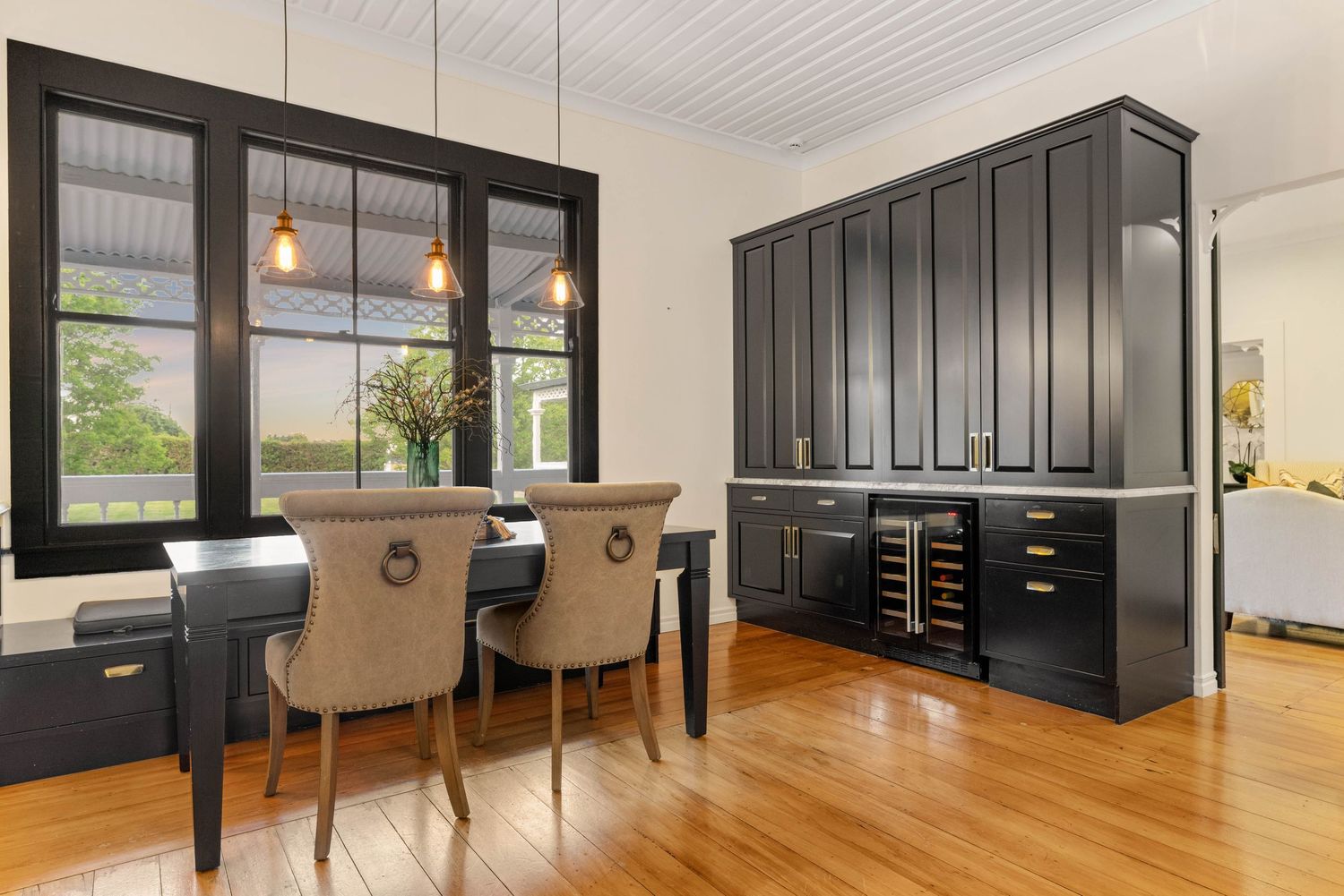 Elegant dining space featuring black cabinetry, upholstered chairs and large windows with natural light.