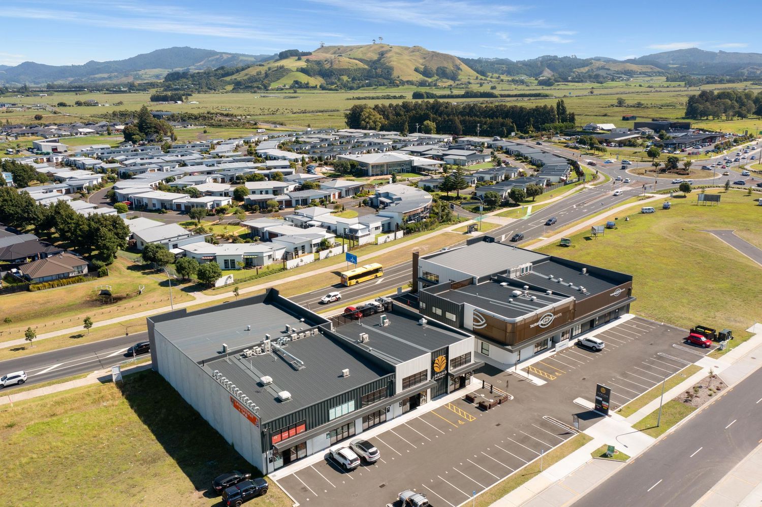 Panoramic drone shot of a shopping center with mountain landscape in the background.