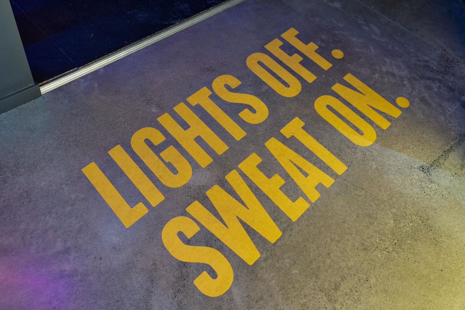 Yellow directional text markings on a dark concrete floor.
