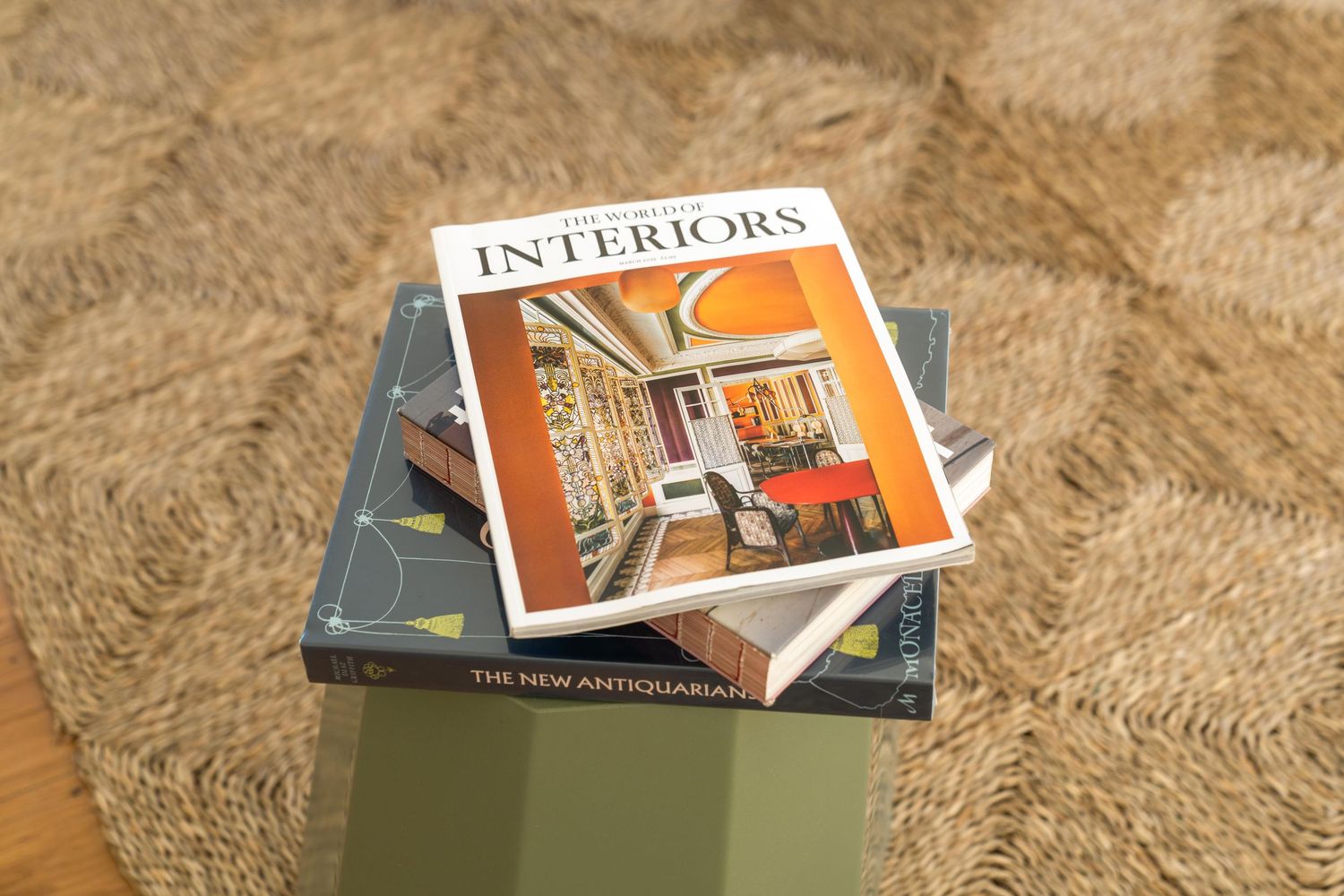 Interior design magazines stacked on a textured beige carpet.