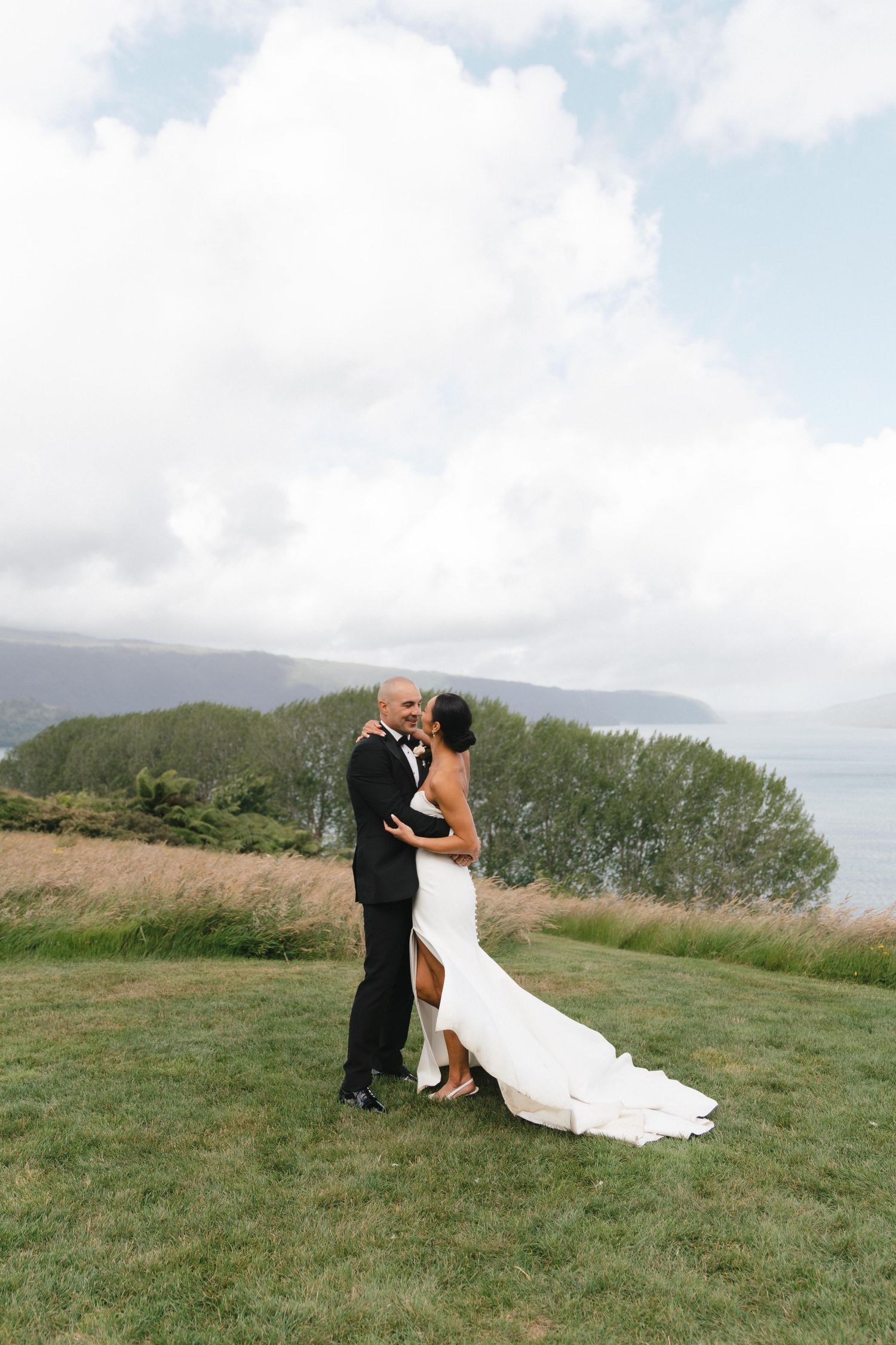 Newlyweds share intimate moments on a hilltop with scenic mountain views in the background.