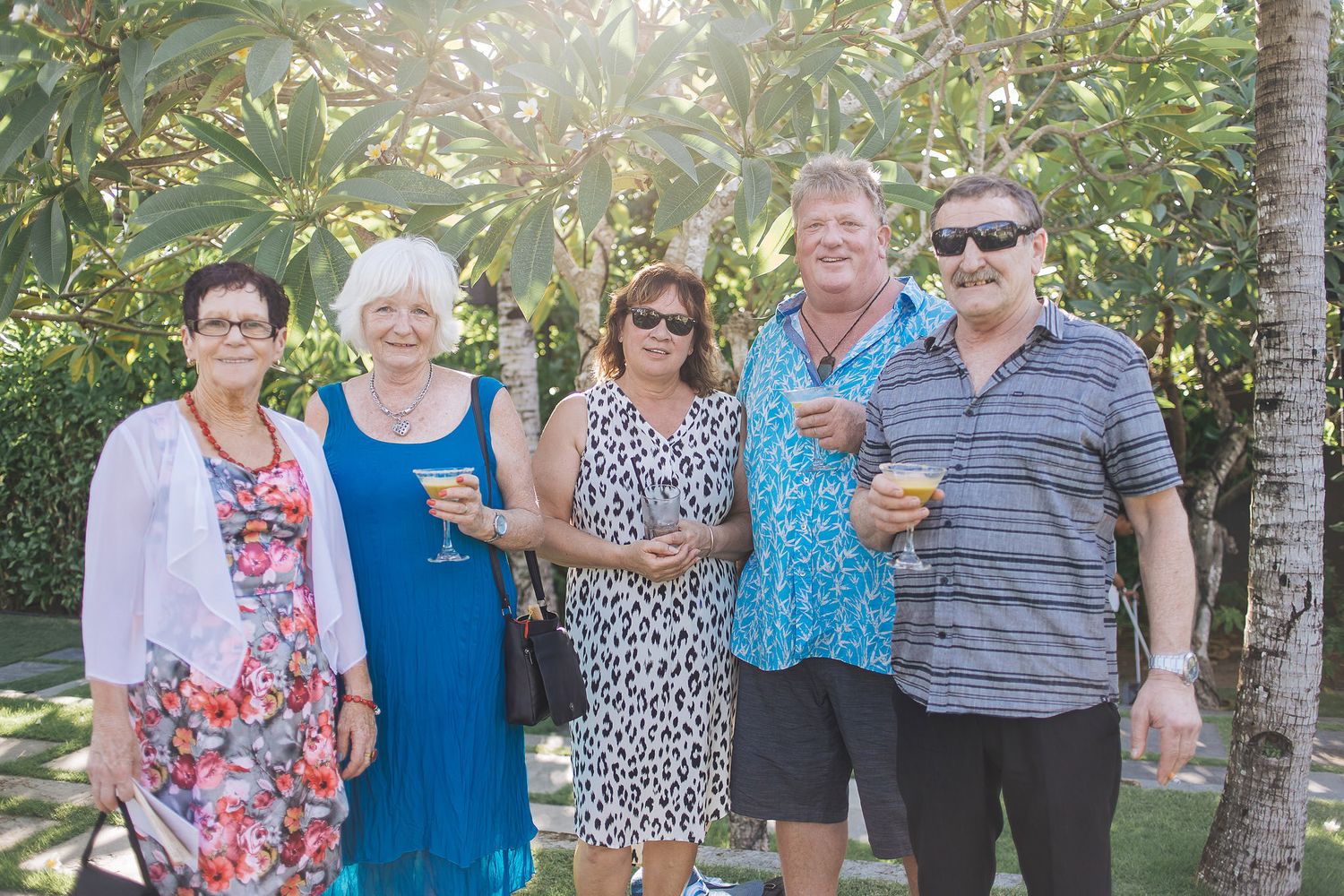 Group of wedding guests posing together in a tropical garden setting.