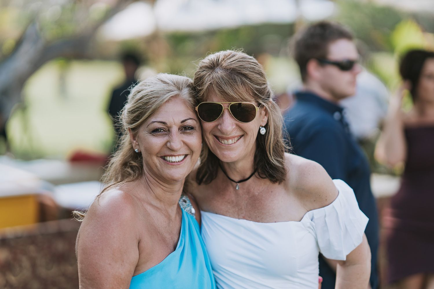 Friends enjoying outdoor celebration in summer attire and sunglasses.