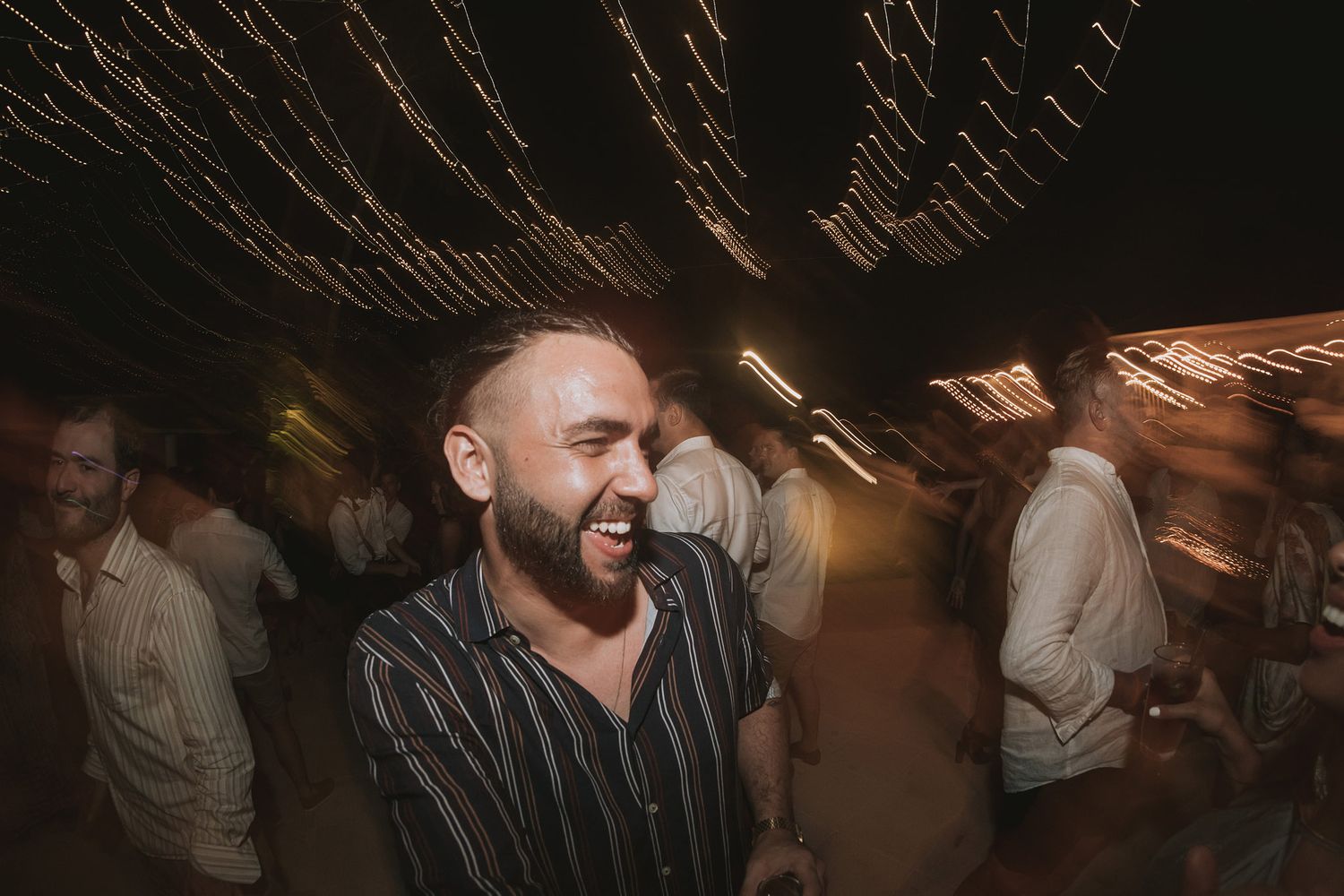 Party scene with dancing and celebration under mood lighting.