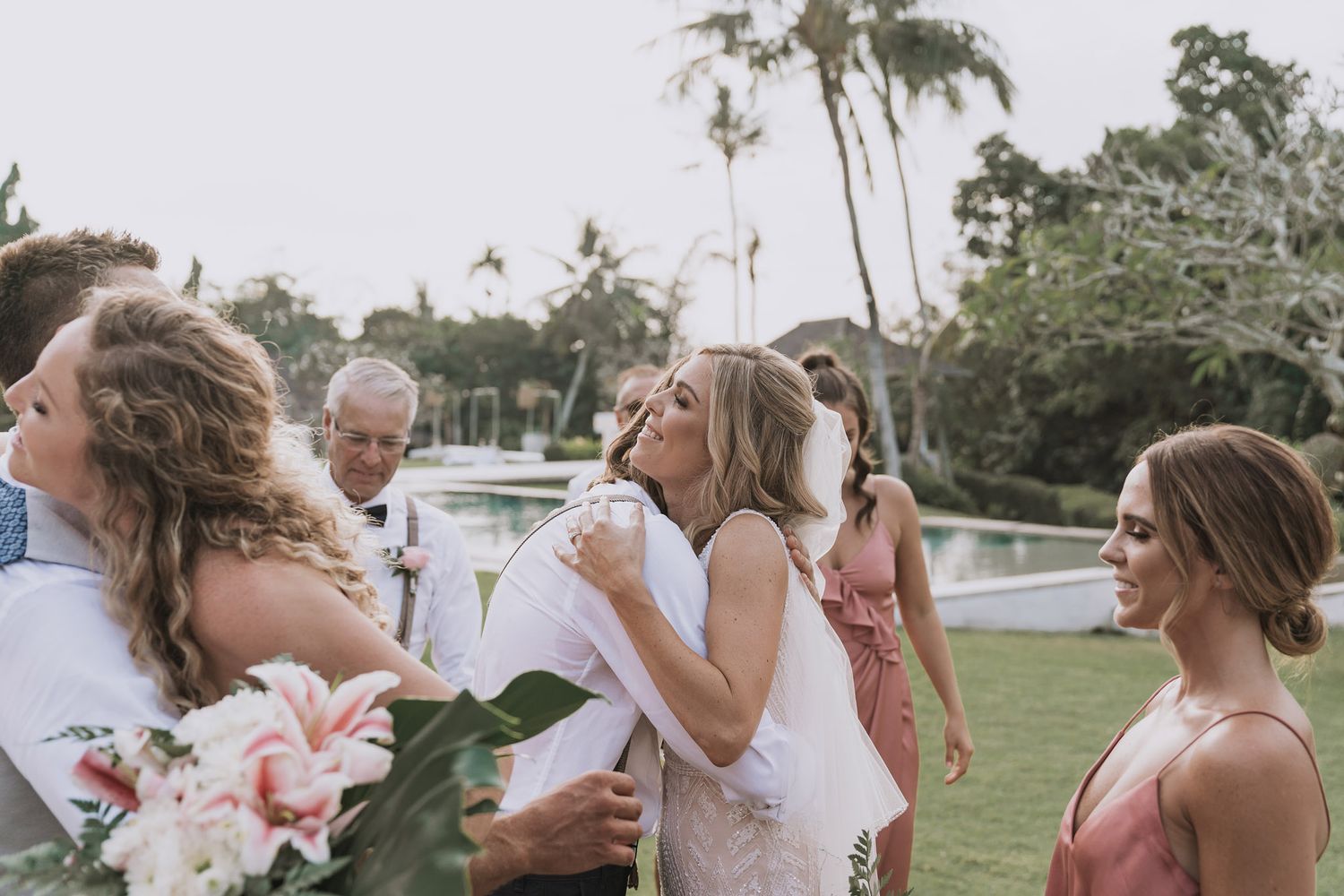 Wedding guests enjoying drinks and dancing at an outdoor reception under palm trees.