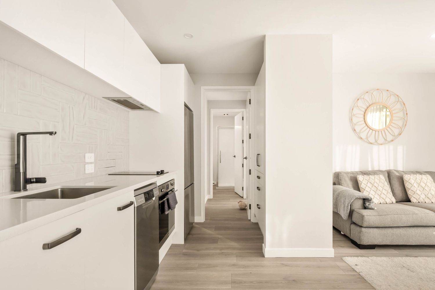 Clean minimalist white hallway with wooden flooring and recessed lighting creating a modern residential atmosphere.