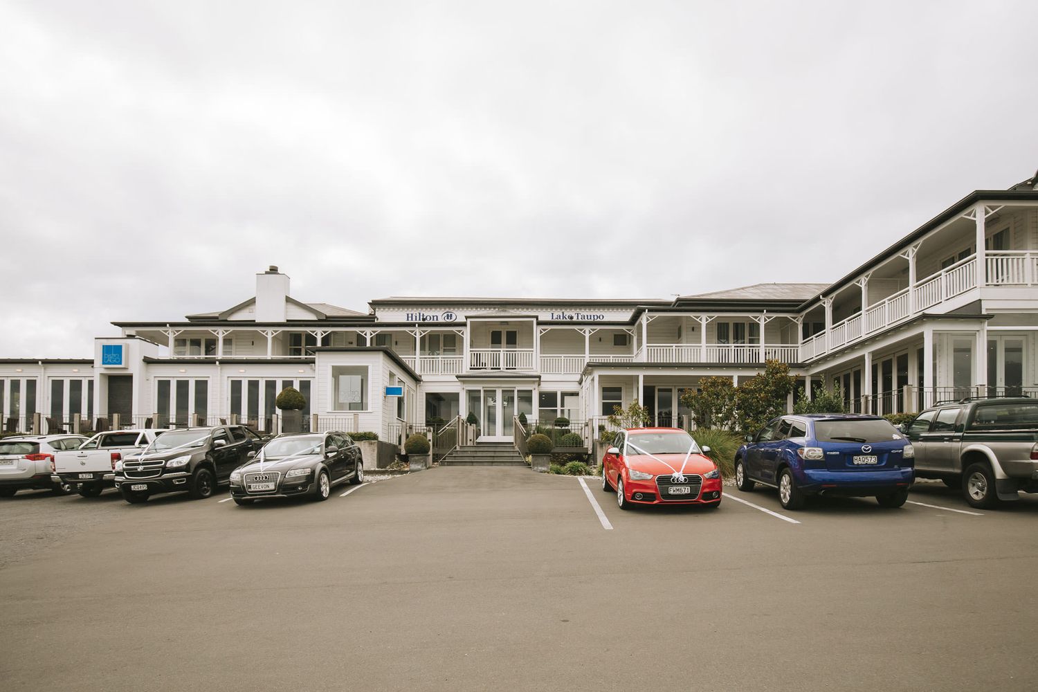 Panoramic view of vintage motel buildings with classic cars parked along multiple white connecting units.