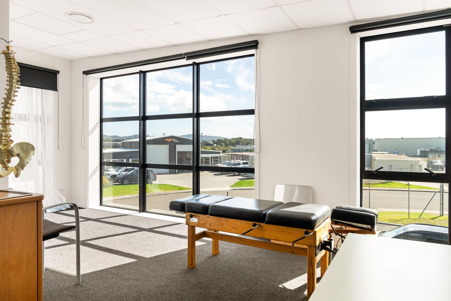 Treatment room with massage table and large windows overlooking scenic landscape.