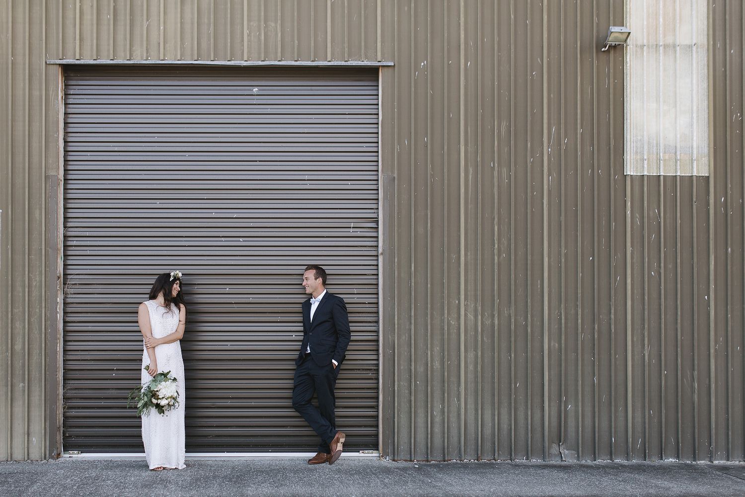Industrial building facade with metal roll-up garage doors and corrugated wall panels.