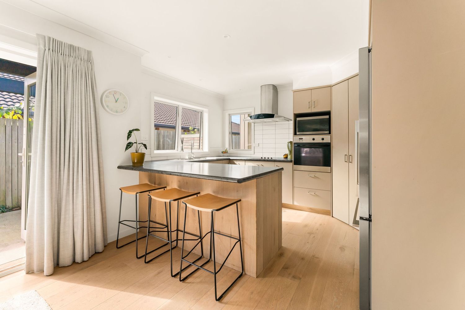 Contemporary bright apartment space with floor-to-ceiling curtains and sleek bar-height seating arrangements.
