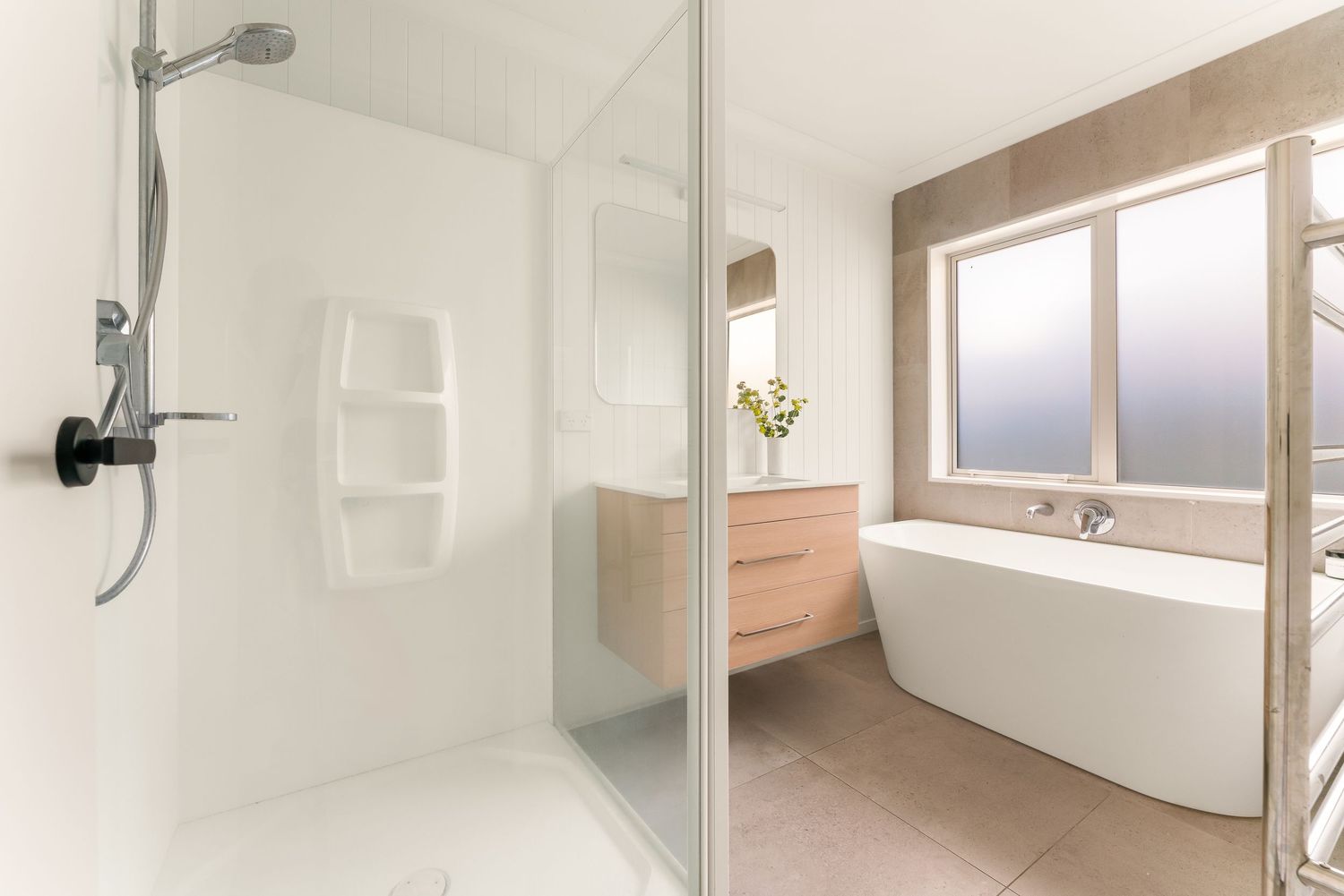 Clean and modern bathroom interior with glass shower enclosure and white tile walls.