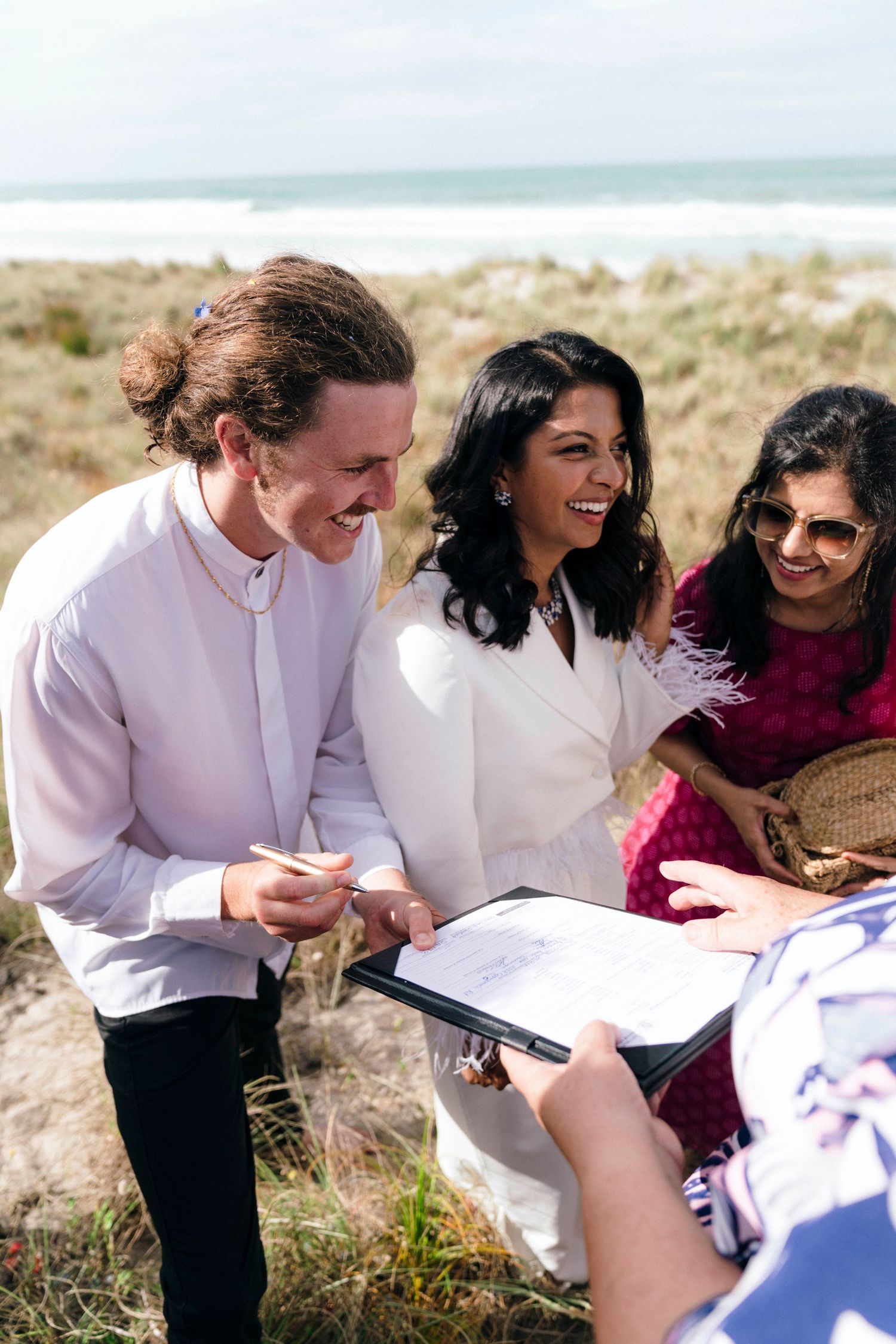 Wedding participants sharing joyful laughter while reviewing paperwork outdoors.