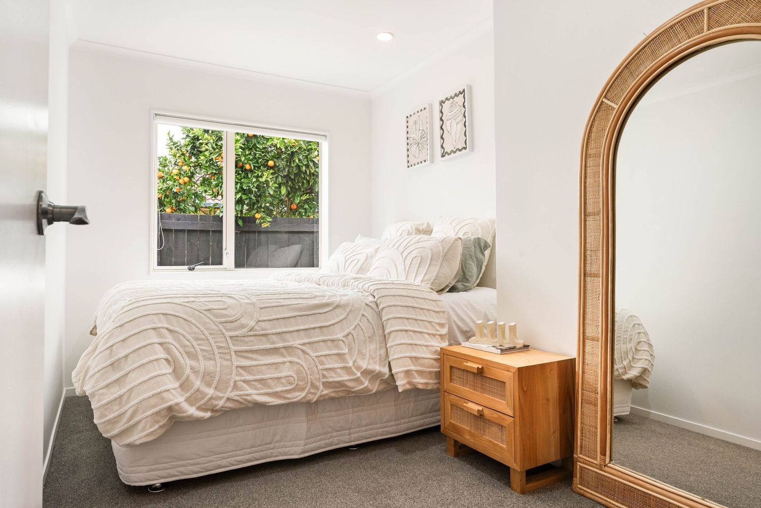 Clean and bright bedroom interior with white bedding and an arched mirror.