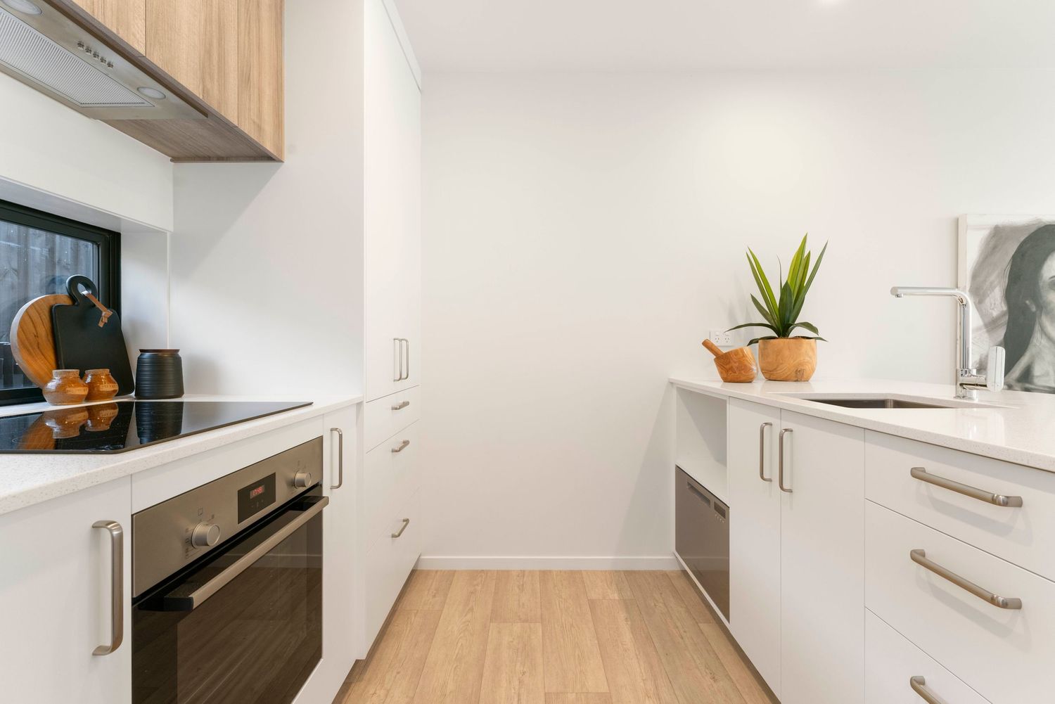 Sleek white kitchen with wood cabinets and stainless appliances in modern minimalist design.