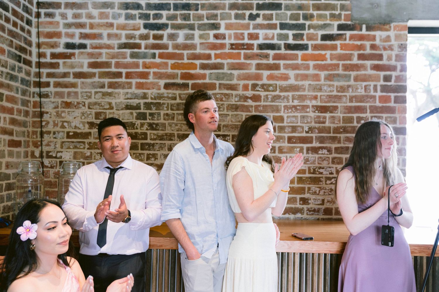 Wedding guests mingling and celebrating in industrial brick venue space.