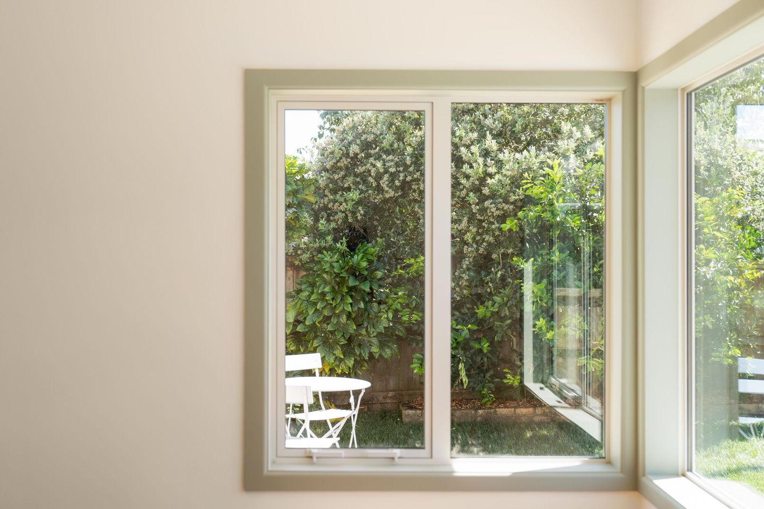 Large panoramic windows line the walls of a bright contemporary room offering views of lush greenery outside.