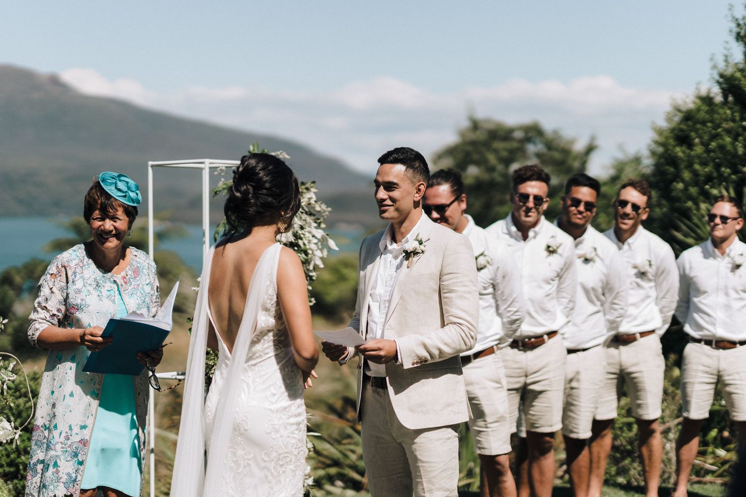 Scenic mountainside wedding ceremony with wedding party in light colored attire.