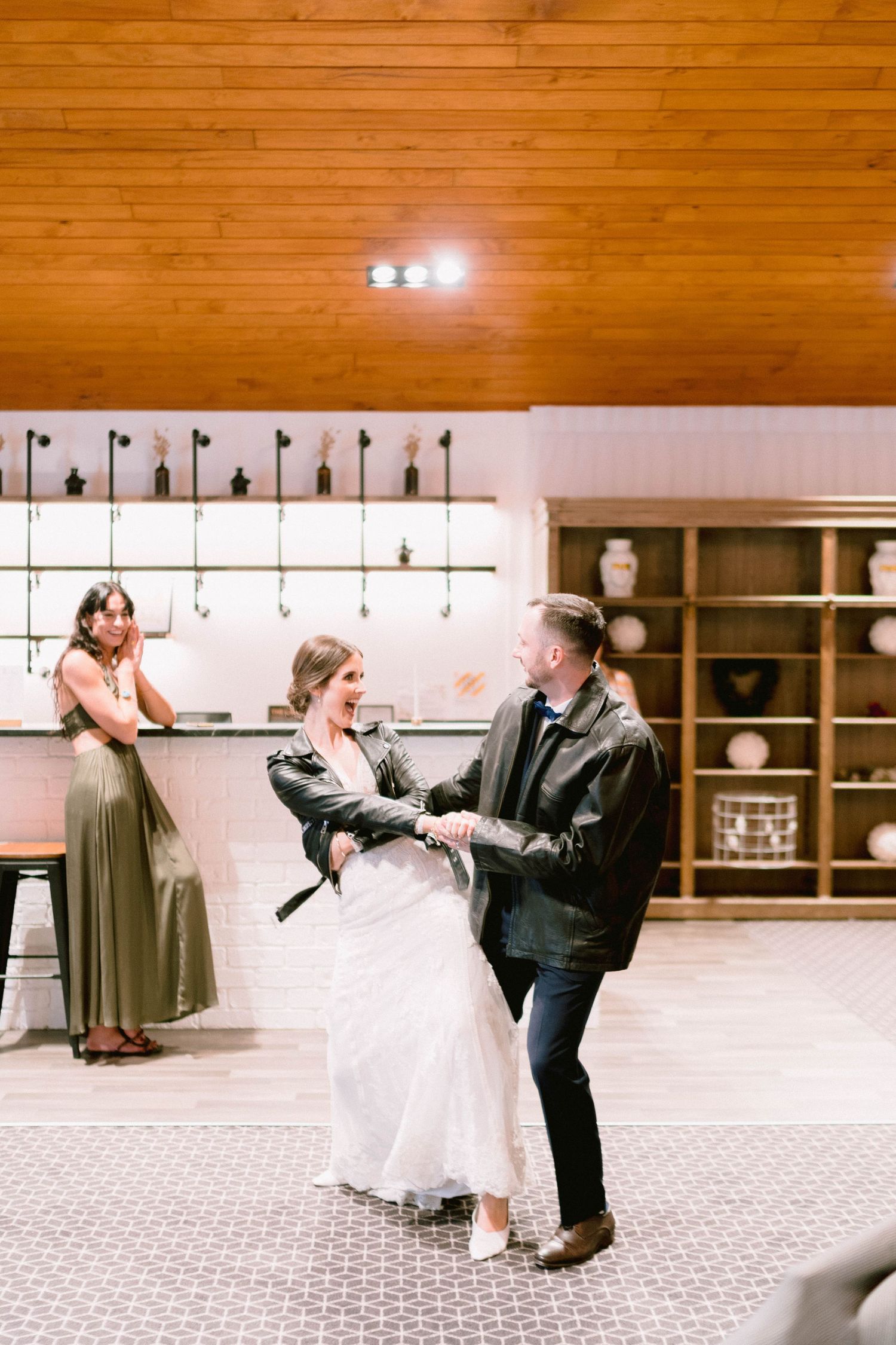 Dance celebration at wedding reception with wood-paneled ceiling.