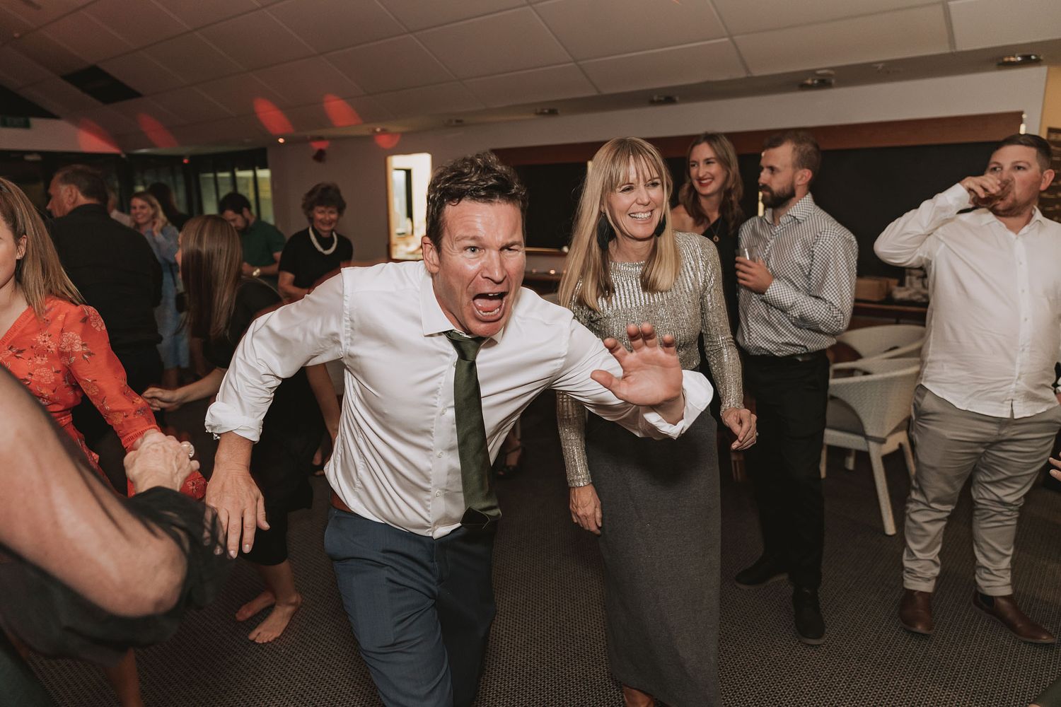 Energetic people dancing and having fun at a party in a dimly lit indoor venue.