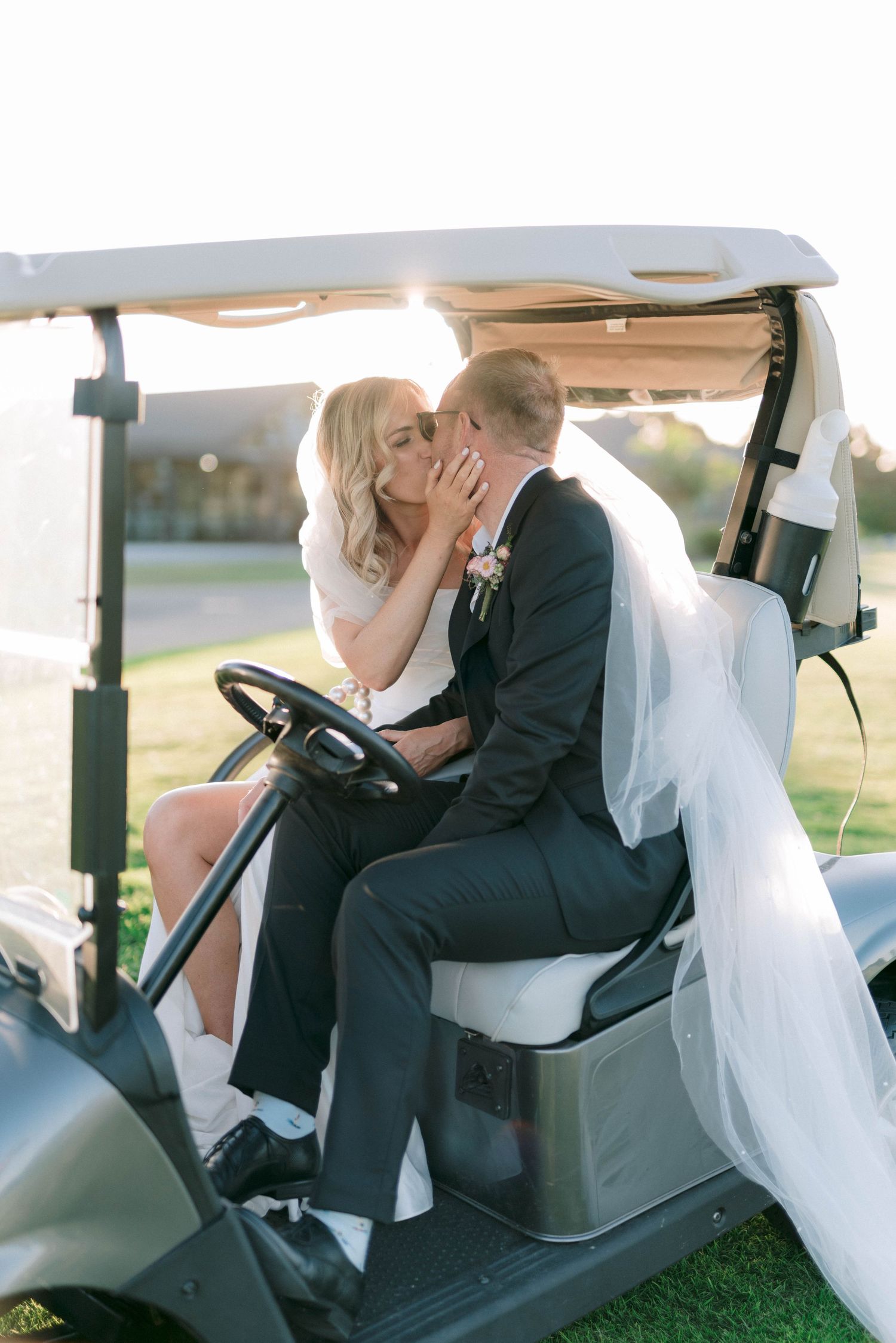 Romantic candid moments of newlyweds sitting together in a golf cart.