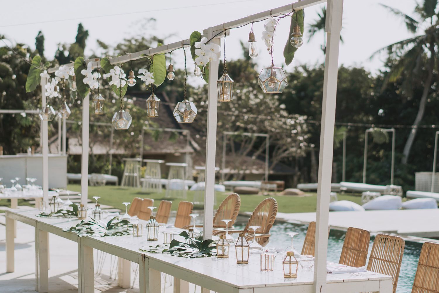 Elegant outdoor wedding reception setup with white canopy and wooden chairs.