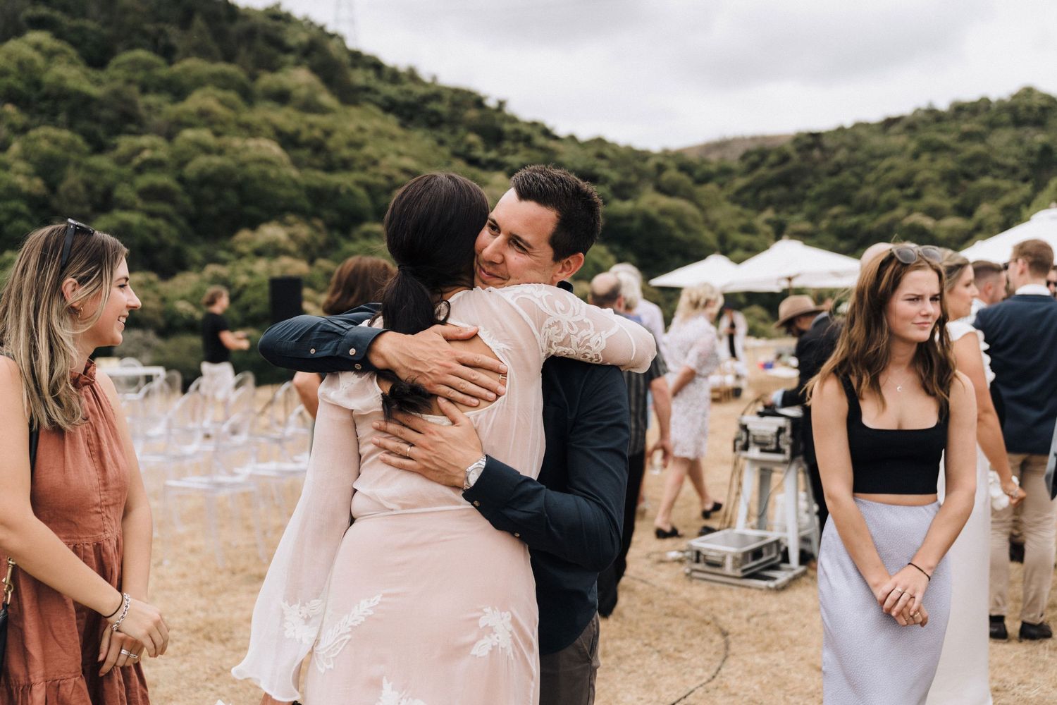 Couples dancing and embracing during a wedding reception on a rustic outdoor venue.