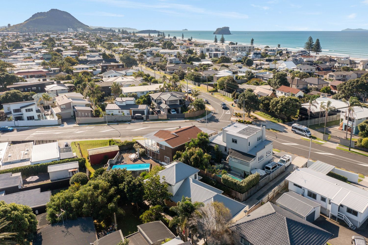 Aerial view of Mount Maunganui coastal neighborhood with beachfront houses and ocean in New Zealand.